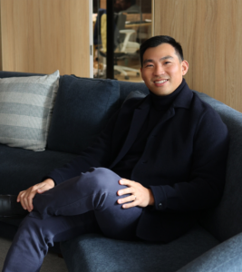 Blossom Health founder John Zhao sitting on a sofa in black turtle neck