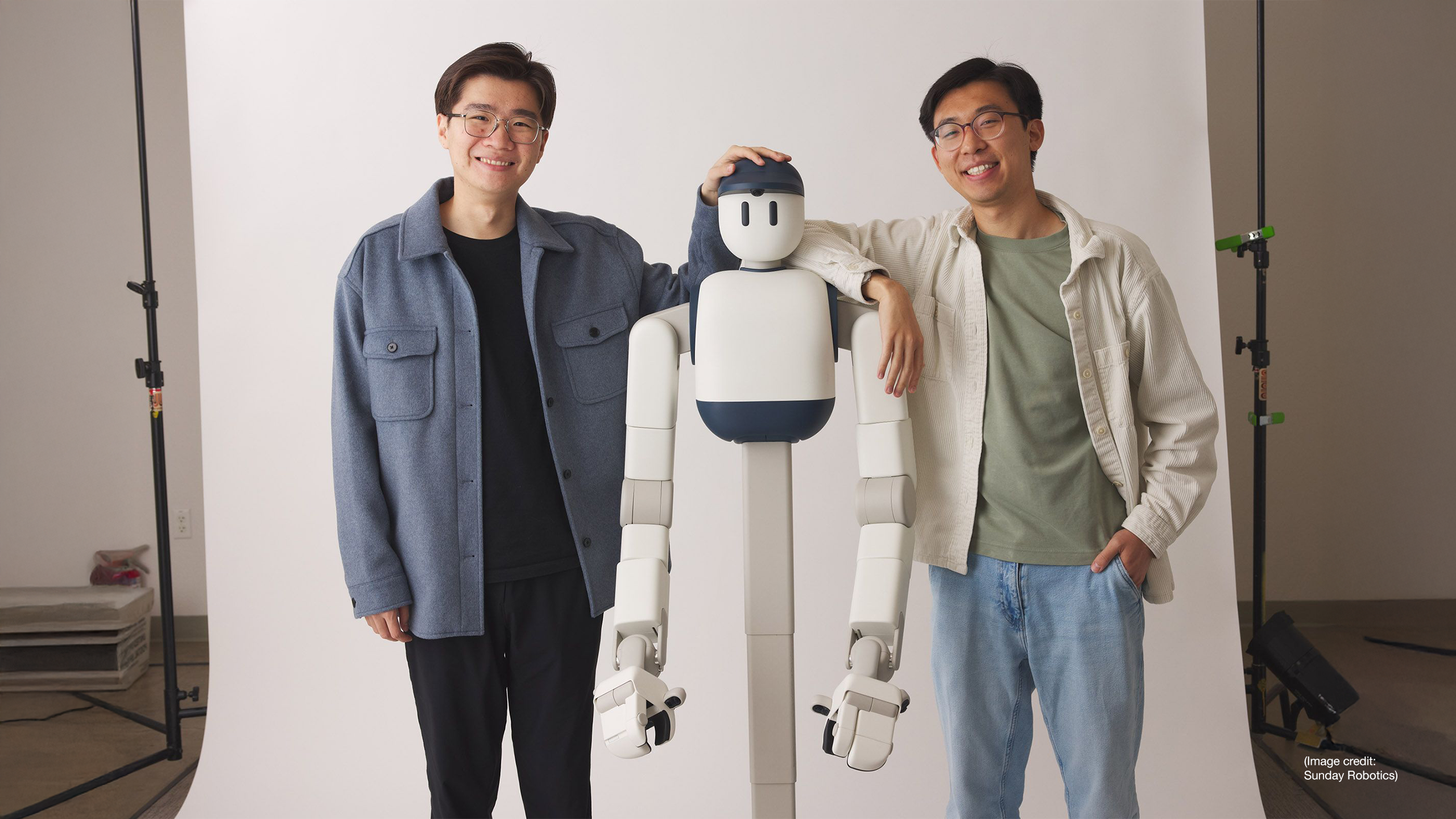 Sunday Robotics co-founders Tony Zhao and Cheng Chi stand next to Memo, their household robot designed to take on everyday chores